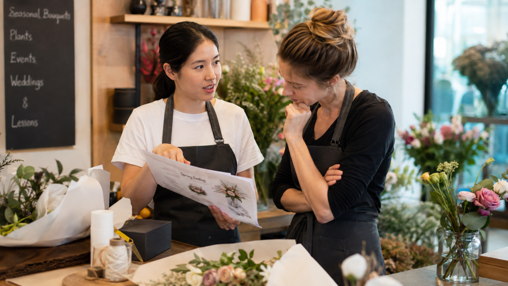 Florist team discussing a customer order in a flower shop, showing consistent brand tone for florists and floral business communication.
